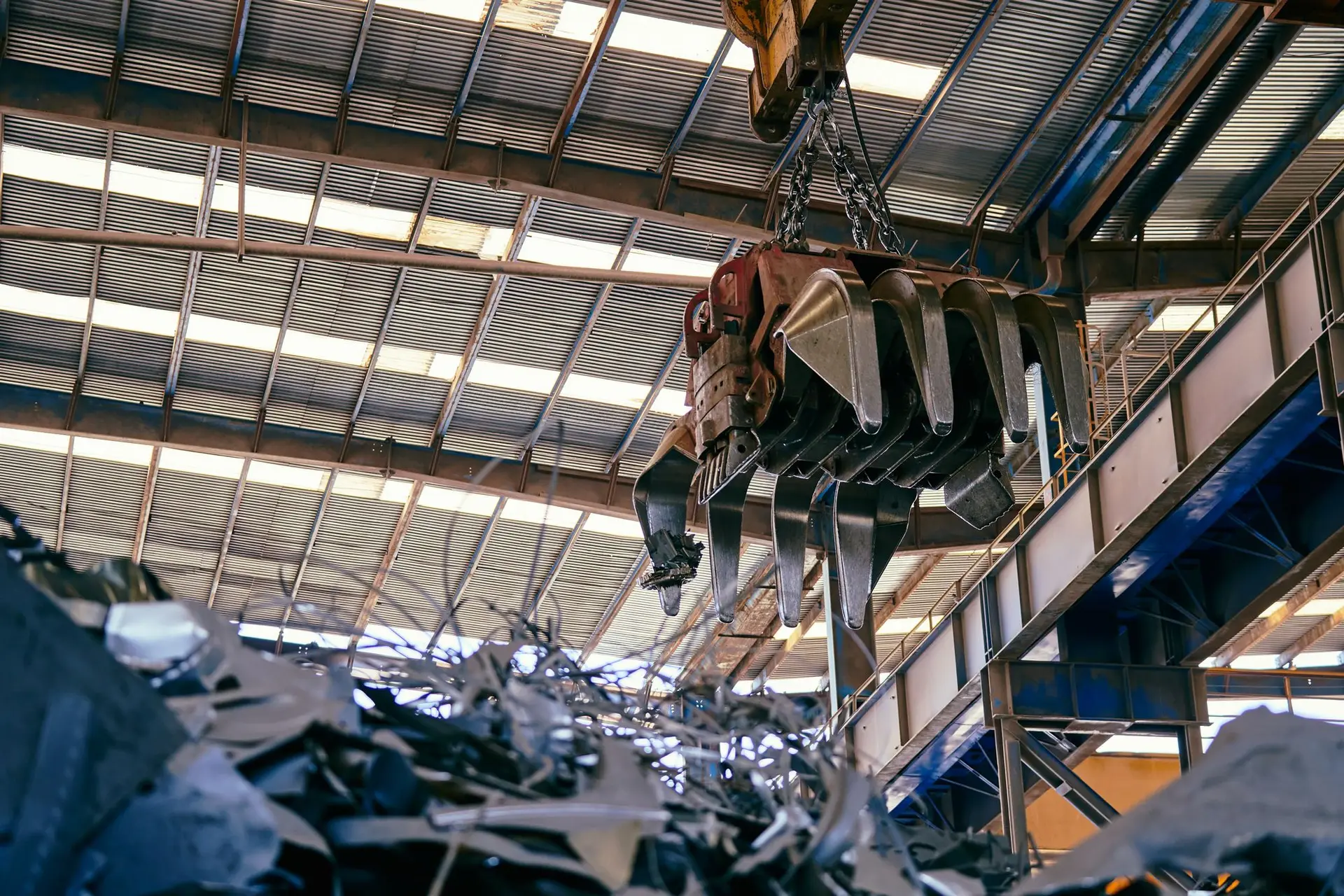 Overhead crane sorting steel scrap in a processing hall